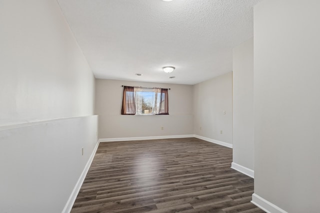 spare room featuring dark wood-type flooring, baseboards, and a textured ceiling