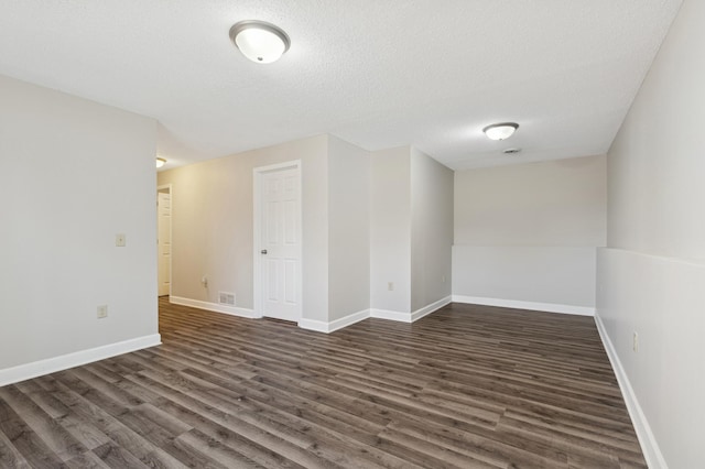 unfurnished room featuring dark wood-type flooring, baseboards, visible vents, and a textured ceiling