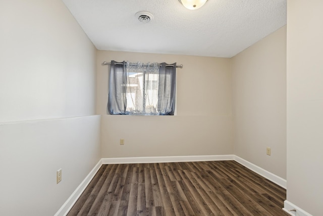 unfurnished room with visible vents, baseboards, a textured ceiling, and wood finished floors