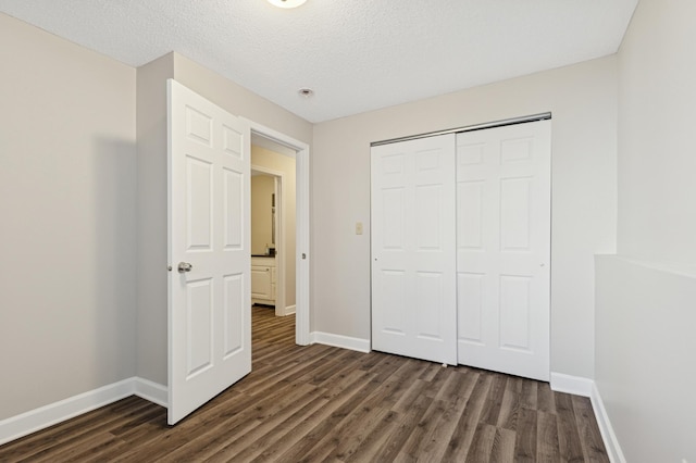 unfurnished bedroom with dark wood-style floors, baseboards, a closet, and a textured ceiling