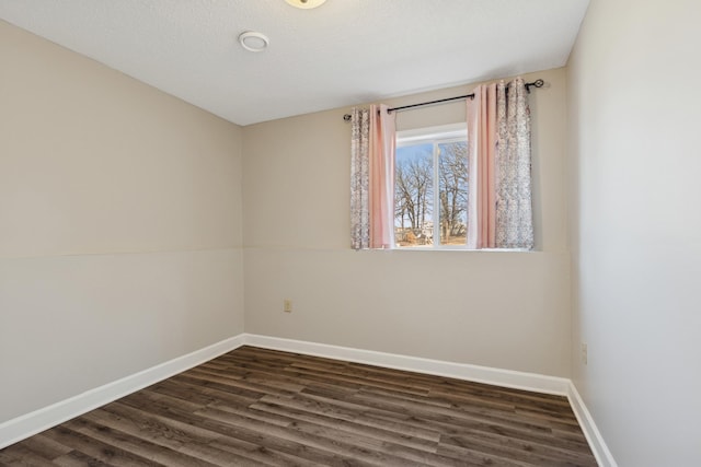 spare room featuring baseboards and dark wood-style flooring