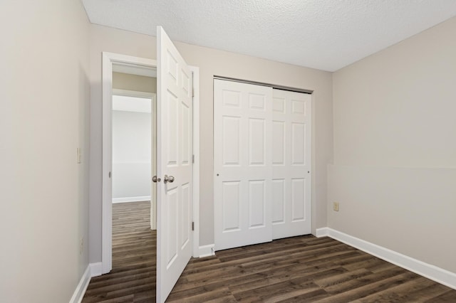 unfurnished bedroom featuring dark wood-type flooring, baseboards, and a textured ceiling