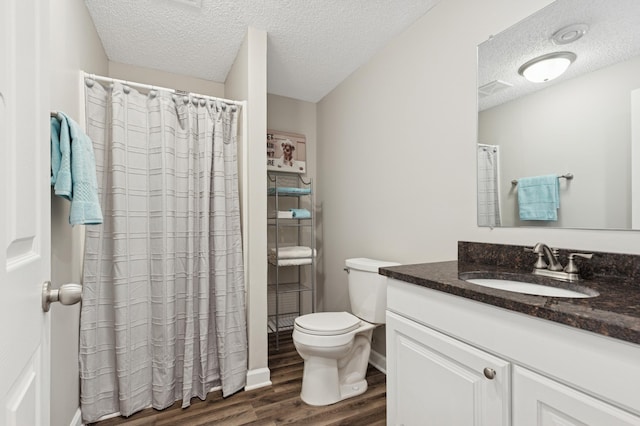 bathroom featuring toilet, wood finished floors, vanity, and a textured ceiling