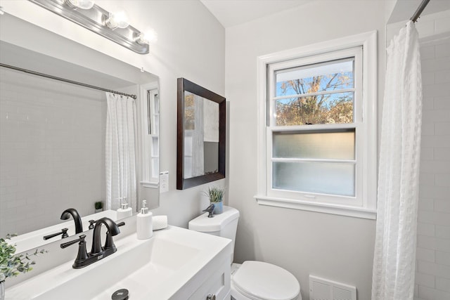 bathroom with walk in shower, vanity, and toilet