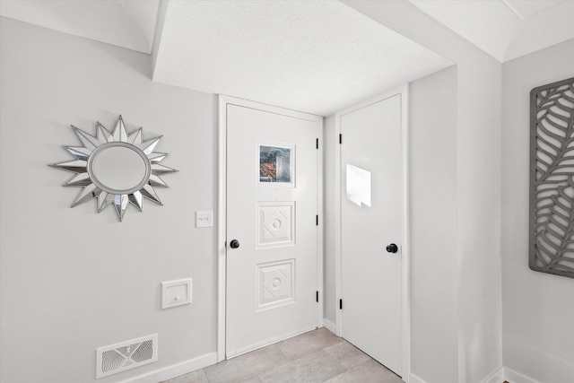 tiled foyer entrance featuring a textured ceiling