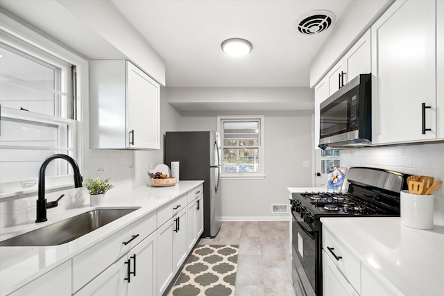 kitchen featuring white cabinets, sink, stainless steel appliances, and tasteful backsplash