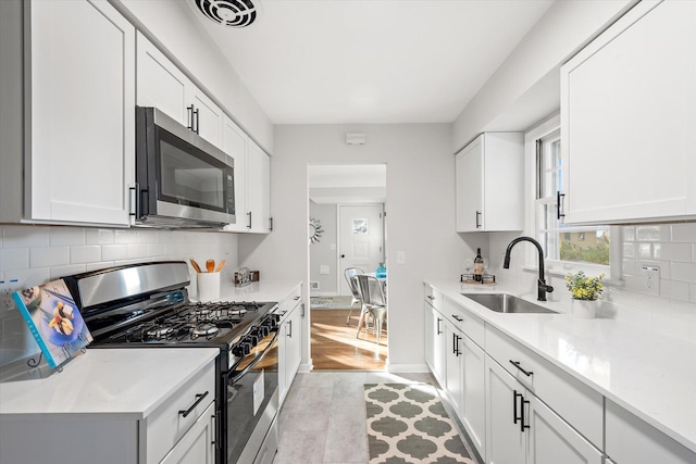 kitchen featuring backsplash, stainless steel appliances, white cabinetry, and sink