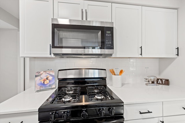 kitchen featuring white cabinets, black gas range, and tasteful backsplash