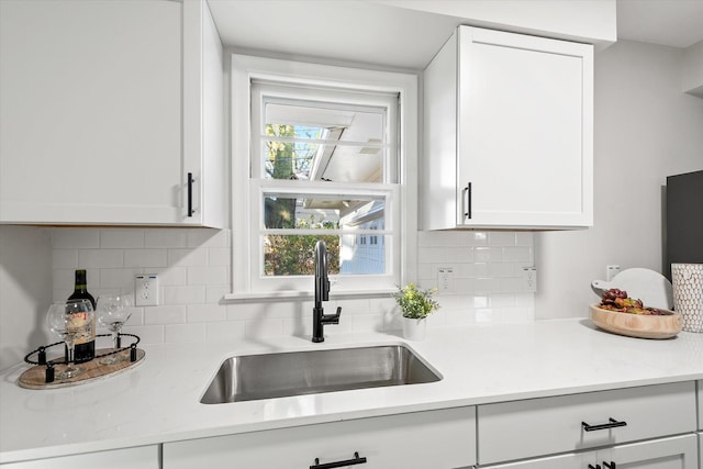 kitchen featuring decorative backsplash, white cabinetry, and sink