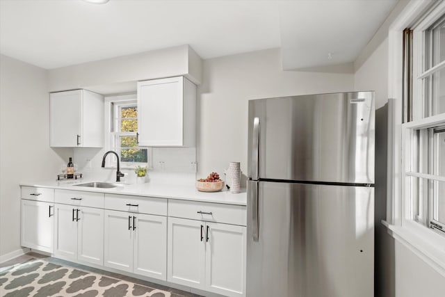 kitchen featuring white cabinets, stainless steel fridge, backsplash, and sink