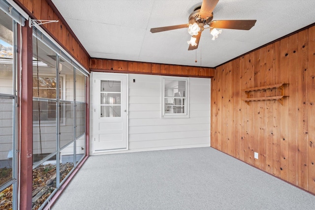 unfurnished room featuring light colored carpet, ceiling fan, and wood walls