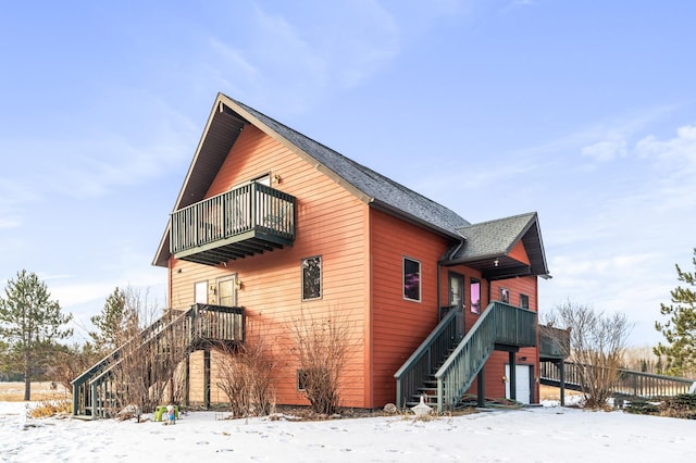 view of snow covered exterior featuring a garage and a balcony