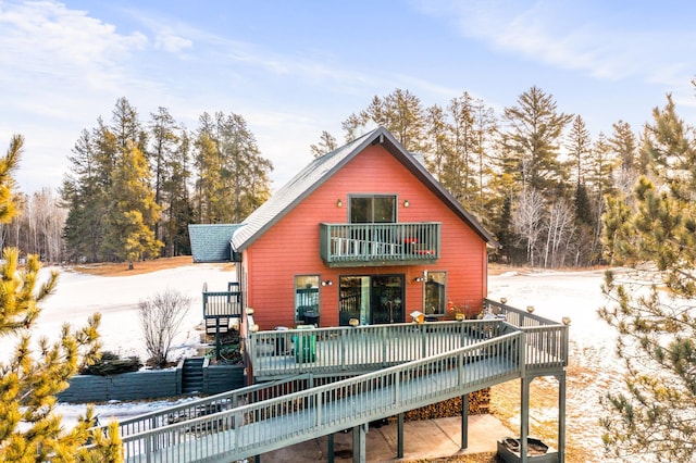 snow covered back of property with a balcony, a deck, and central air condition unit