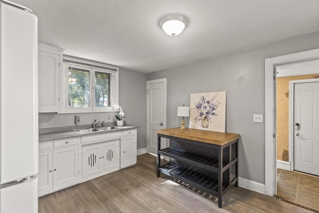 bar with white cabinets, light wood-type flooring, white fridge, and sink