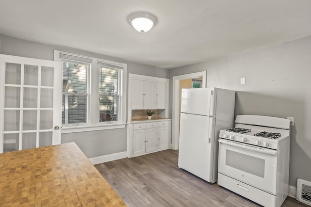 kitchen with white appliances, light hardwood / wood-style flooring, decorative backsplash, butcher block countertops, and white cabinetry