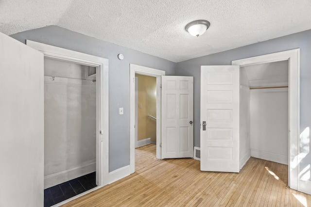 unfurnished bedroom featuring lofted ceiling, light hardwood / wood-style floors, and a textured ceiling