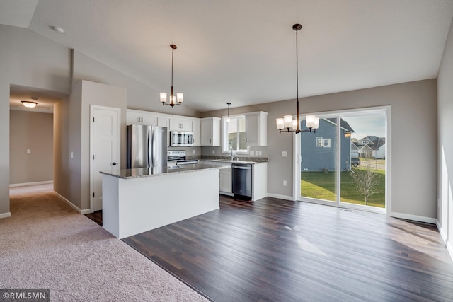 kitchen with a kitchen island, white cabinets, hanging light fixtures, and appliances with stainless steel finishes