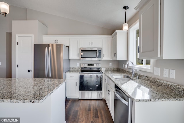 kitchen featuring vaulted ceiling, decorative light fixtures, light stone counters, white cabinetry, and stainless steel appliances