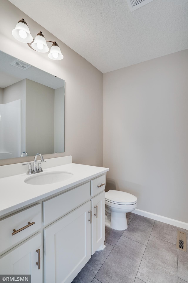 bathroom with tile patterned floors, vanity, a textured ceiling, and toilet