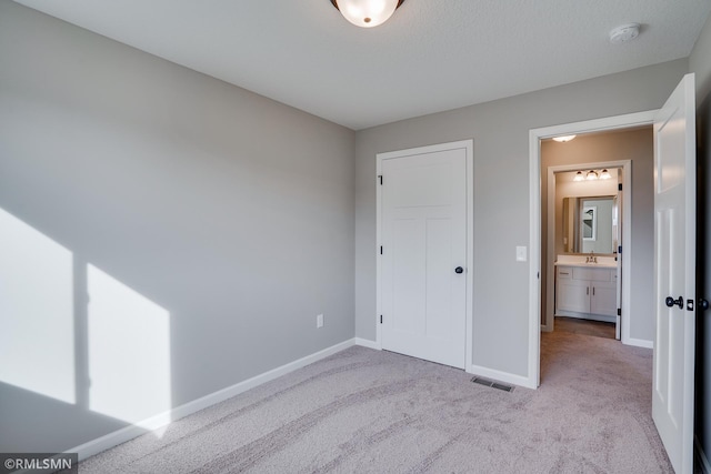 unfurnished bedroom featuring sink and light carpet