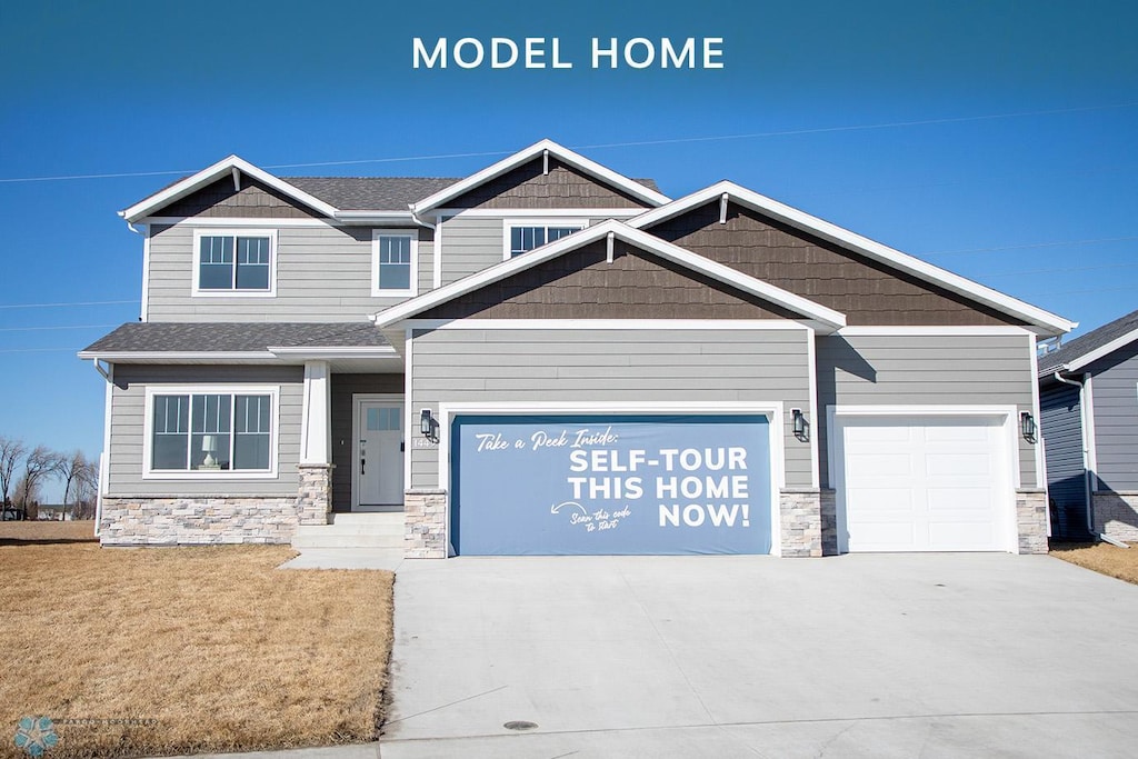 1449 66th Ave S, Fargo, ND 58104 - craftsman house featuring stone siding, a garage, concrete driveway, and a front yard