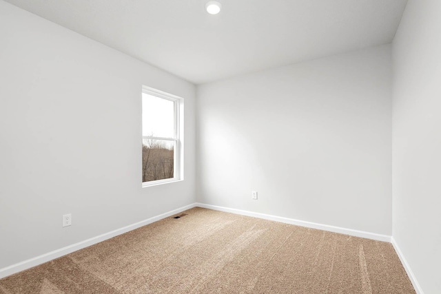 empty room featuring carpet floors, visible vents, and baseboards