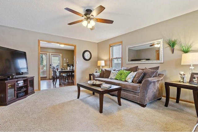 living room with ceiling fan, light colored carpet, and a textured ceiling