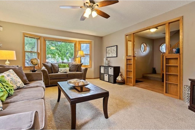 carpeted living room featuring ceiling fan and a textured ceiling