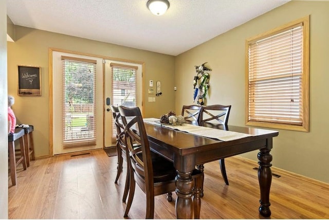 dining space with a textured ceiling and light hardwood / wood-style flooring