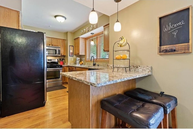 kitchen featuring kitchen peninsula, a breakfast bar, hanging light fixtures, and appliances with stainless steel finishes