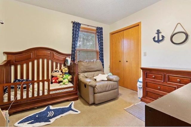 carpeted bedroom with a nursery area, a textured ceiling, and a closet