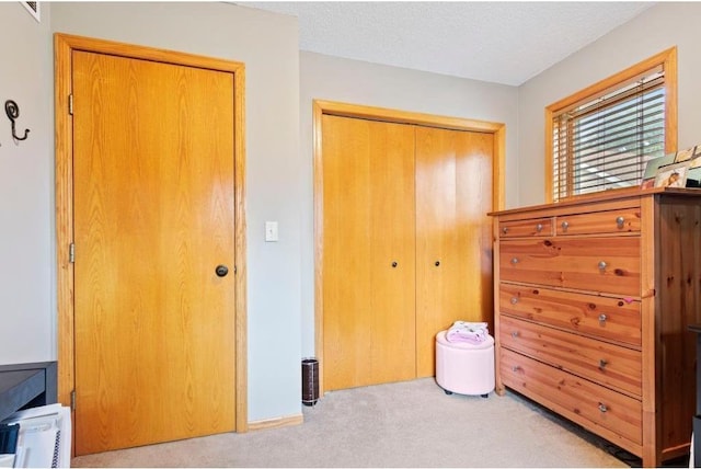 bedroom featuring a textured ceiling, light colored carpet, and a closet