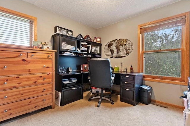 carpeted home office featuring a textured ceiling