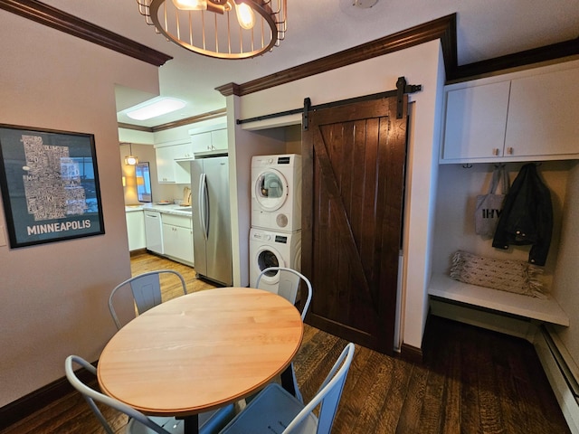 dining area featuring a barn door, wood-type flooring, ornamental molding, and stacked washer and dryer