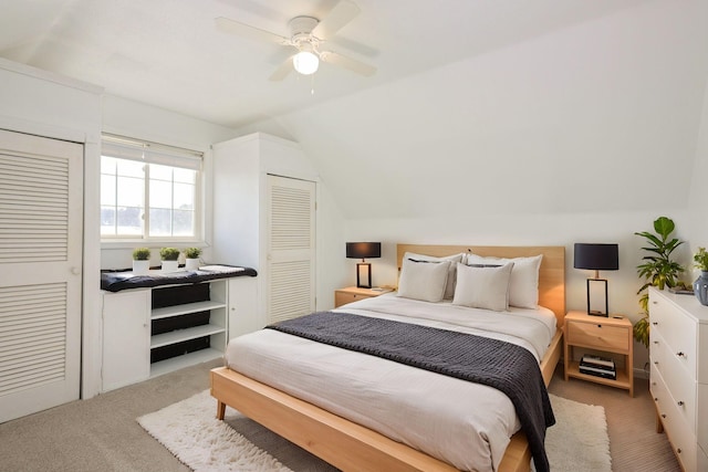 bedroom with a ceiling fan, carpet, vaulted ceiling, and two closets