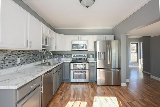 kitchen featuring decorative backsplash, gray cabinets, crown molding, stainless steel appliances, and a sink