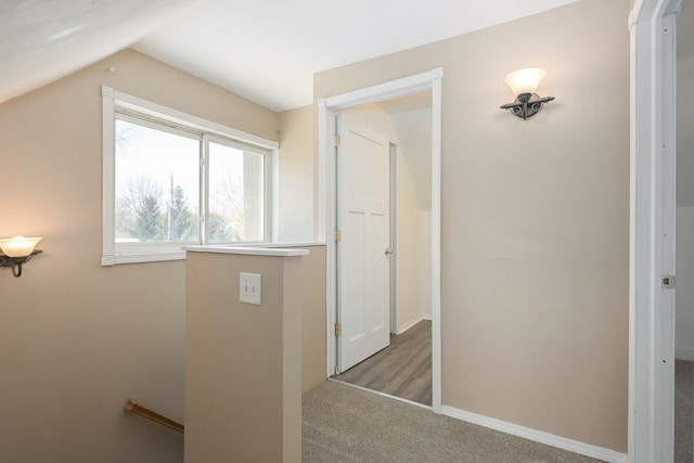 hall with carpet floors, an upstairs landing, baseboards, and lofted ceiling