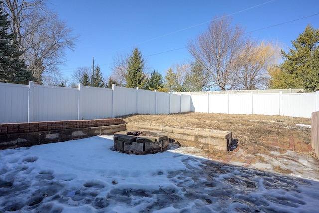 yard layered in snow featuring a fire pit and a fenced backyard