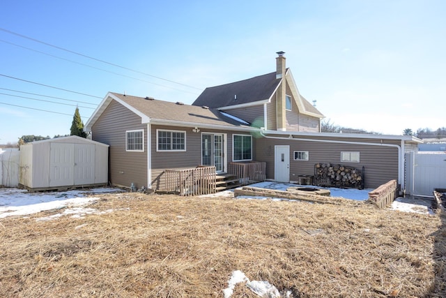 back of property with a shed, a chimney, an outdoor structure, and fence