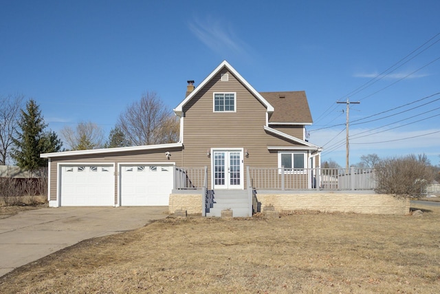 view of front of house with driveway, a garage, a chimney, roof with shingles, and french doors