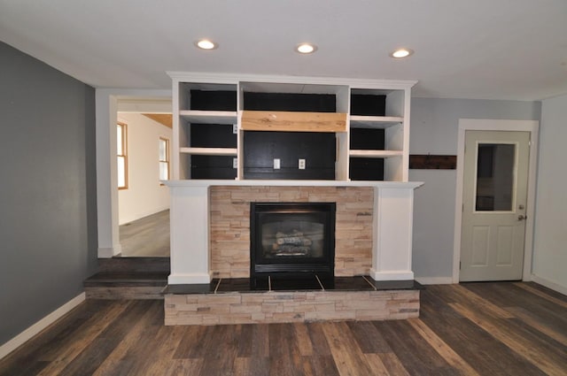 unfurnished living room with dark hardwood / wood-style flooring, built in shelves, and a fireplace