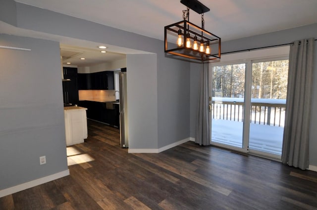 unfurnished dining area featuring dark hardwood / wood-style flooring and an inviting chandelier