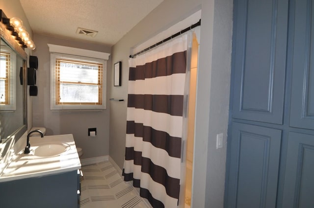 bathroom with a textured ceiling, vanity, and curtained shower