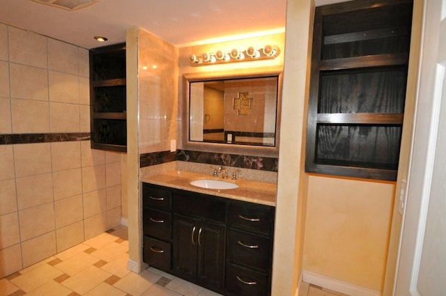 bathroom featuring tile patterned flooring, vanity, and tile walls