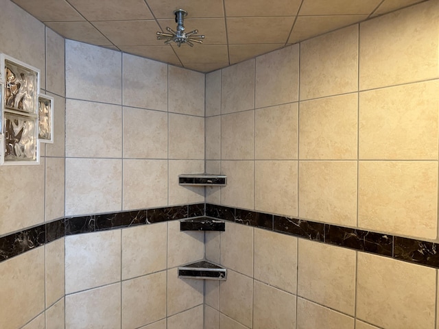 interior details featuring a tile shower and ceiling fan