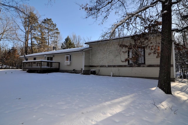 snow covered back of property featuring a deck