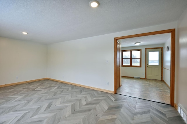 spare room with a textured ceiling and light parquet floors