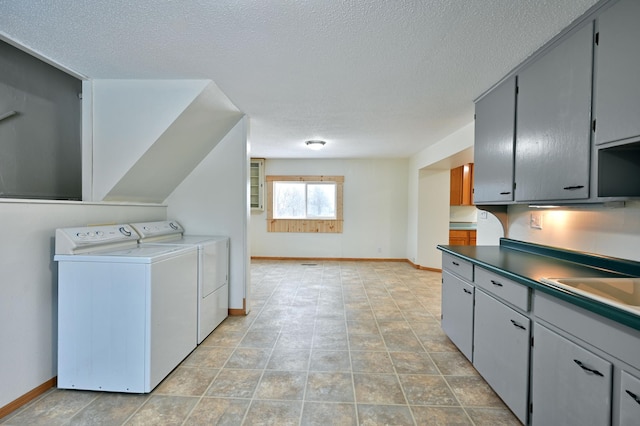 clothes washing area with separate washer and dryer, sink, cabinets, and a textured ceiling