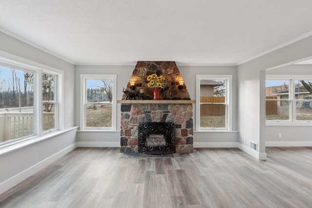 unfurnished living room with light hardwood / wood-style floors, a wealth of natural light, crown molding, and a fireplace