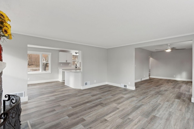 unfurnished living room featuring ceiling fan, light hardwood / wood-style floors, crown molding, and a fireplace